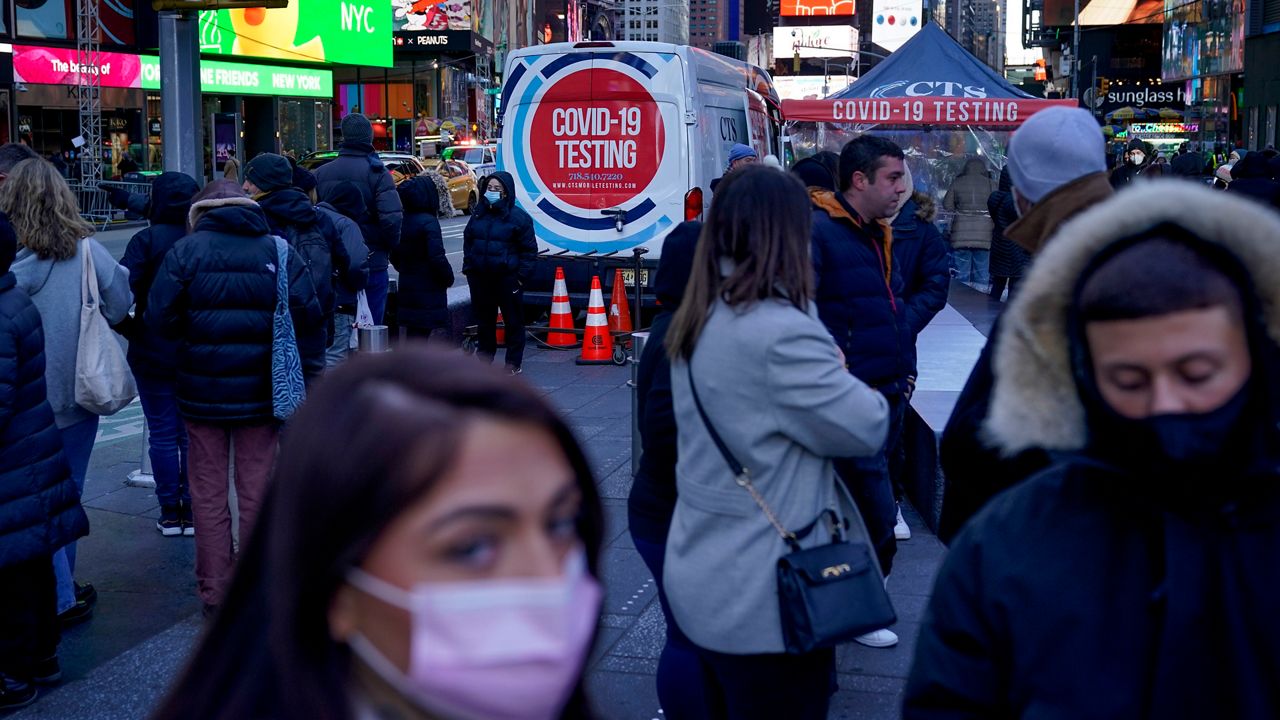 People wearing masks stand in front a long line for COVID-19 testing near a van in Times Square.