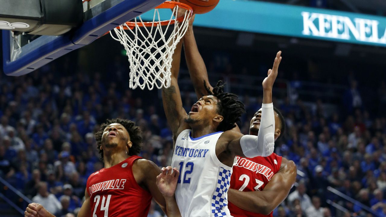 Kentucky's Keion Brooks Jr. (12) shoots between Louisville's Dwayne Sutton (24) and Steven Enoch during the first half of an NCAA college basketball game in Lexington, Ky., Saturday, Dec. 28, 2019. (AP Photo/James Crisp)