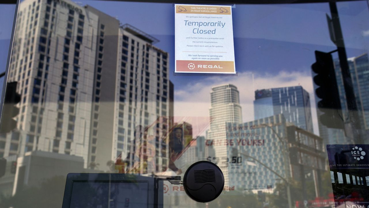 A "temporarily closed" sign sits on the box office window of the Regal Cinemas L.A. Live Stadium 14 movie theaters, Tuesday, Aug. 18, 2020, in Los Angeles. (AP Photo/Chris Pizzello)