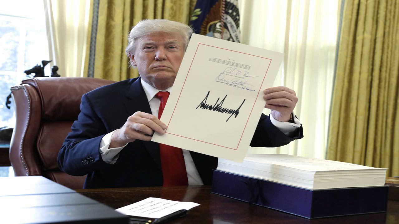 President Donald Trump displays the $1.5 trillion tax overhaul package he had just signed, Friday, Dec. 22, 2017, in the Oval Office of the White House in Washington. Trump touted the size of the tax cut, declaring to reporters in the Oval Office before he signed it Friday that "the numbers will speak." (AP Photo/Evan Vucci)