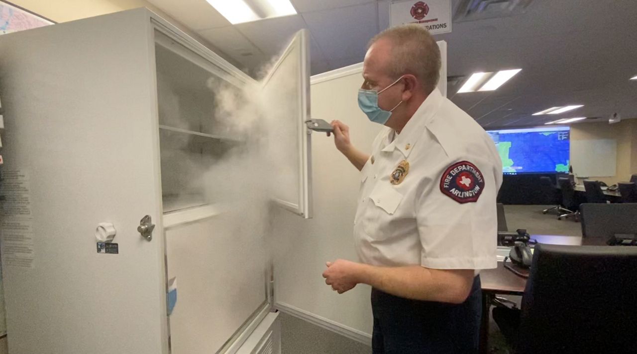 Assistant Chief Gerald Randall of the Arlington Fire Department opens freezer where COVID-19 vaccines are being stored. (Spectrum News 1)