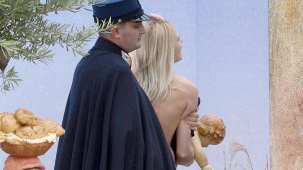 A guard from the Vatican's security forces stops a Ukrainian feminist group Femen activist after she snatched the statue of baby Jesus from the Nativity scene set in St. Peter's Square at the Vatican, Thursday, Dec. 25, 2014. (Image/AP)