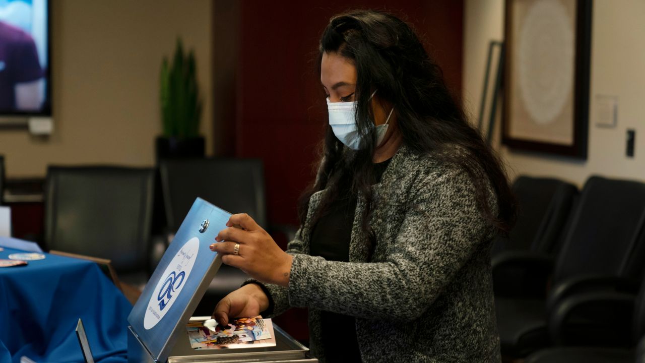 Former COVID-19 patient, Patricia Gomez, 32, places some pictures into a time capsule at Providence Mission Hospital in Mission Viejo, Calif., Thursday, Dec. 9, 2021, as former coronavirus patients and their caregivers gather to celebrate the hospital's 50th anniversary. (AP Photo/Jae C. Hong)