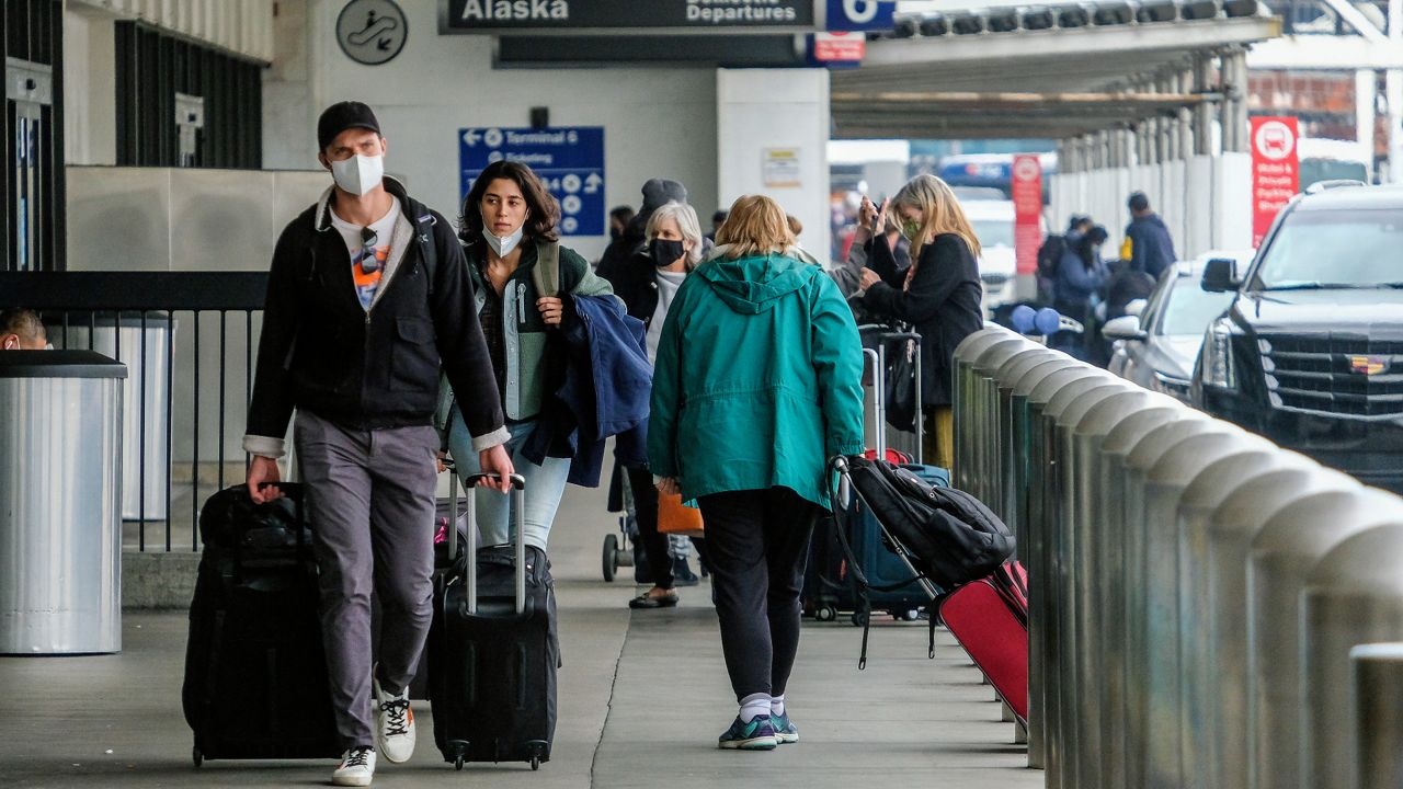 Holiday travelers wearing face masks arrive at the Los Angeles International Airport in Los Angeles, Wednesday, Dec. 22, 2021. (AP Photo/Ringo H.W. Chiu)