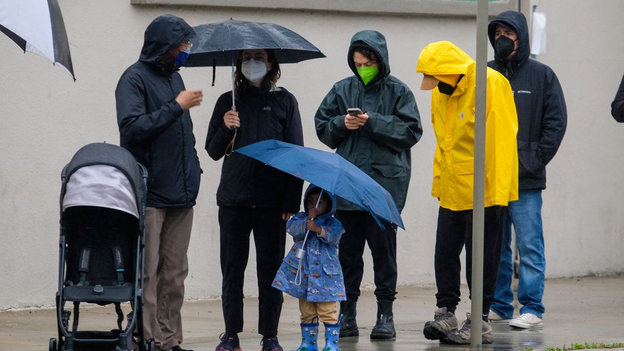 People with umbrellas wait in line for a free COVID-19 test outside Lincoln Park Recreation Center in Los Angeles on Thursday, Dec. 23, 2021. (AP Photo/Ringo H.W. Chiu)
