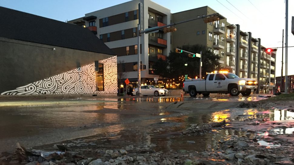 Water spills over the road after a water main break in downtown Austin. (Spectrum News photograph)