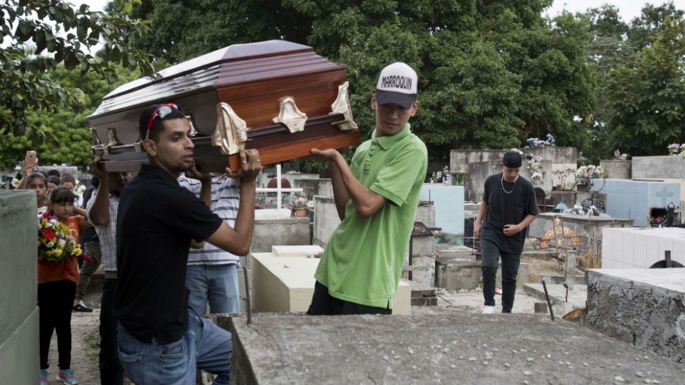In this Oct. 31, 2018 photo, relatives hoist the coffin that contains the remains of Wilmer Gerardo Nunez onto a burial site at a cemetery in San Pedro Sula, Honduras. Nunez was not the oldest of the 10 children in the family, but he was the one who looked out for the others. He sent money home from the U.S. and called his mother almost every day. (AP Photo/Moises Castillo)