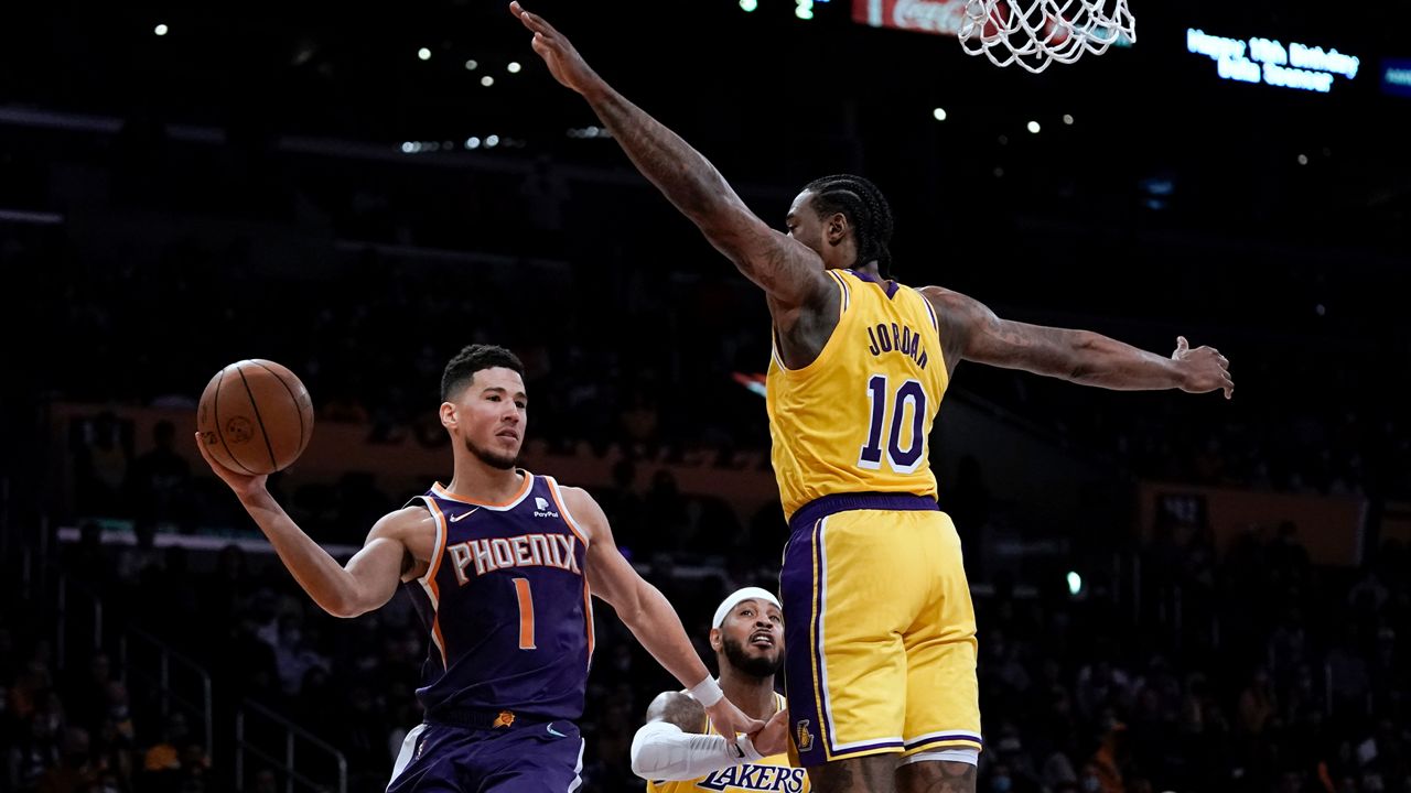 Phoenix Suns' Devin Booker, left, passes as Los Angeles Lakers' DeAndre Jordan defends during first half of an NBA basketball game Tuesday, Dec. 21, 2021, in Los Angeles. (AP Photo/Jae C. Hong)