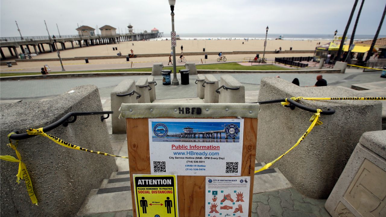 A sign gives social distance and hand washing guidelines Thursday, April 30, 2020, in Huntington Beach, Calif. California Gov. Gavin Newsom has ordered beaches in Orange County to close until further notice amid the COVID-19 pandemic. Newsom made the announcement Thursday, days after tens of thousands of people in Orange County packed beaches during a sunny weekend. (AP Photo/Marcio Jose Sanchez)