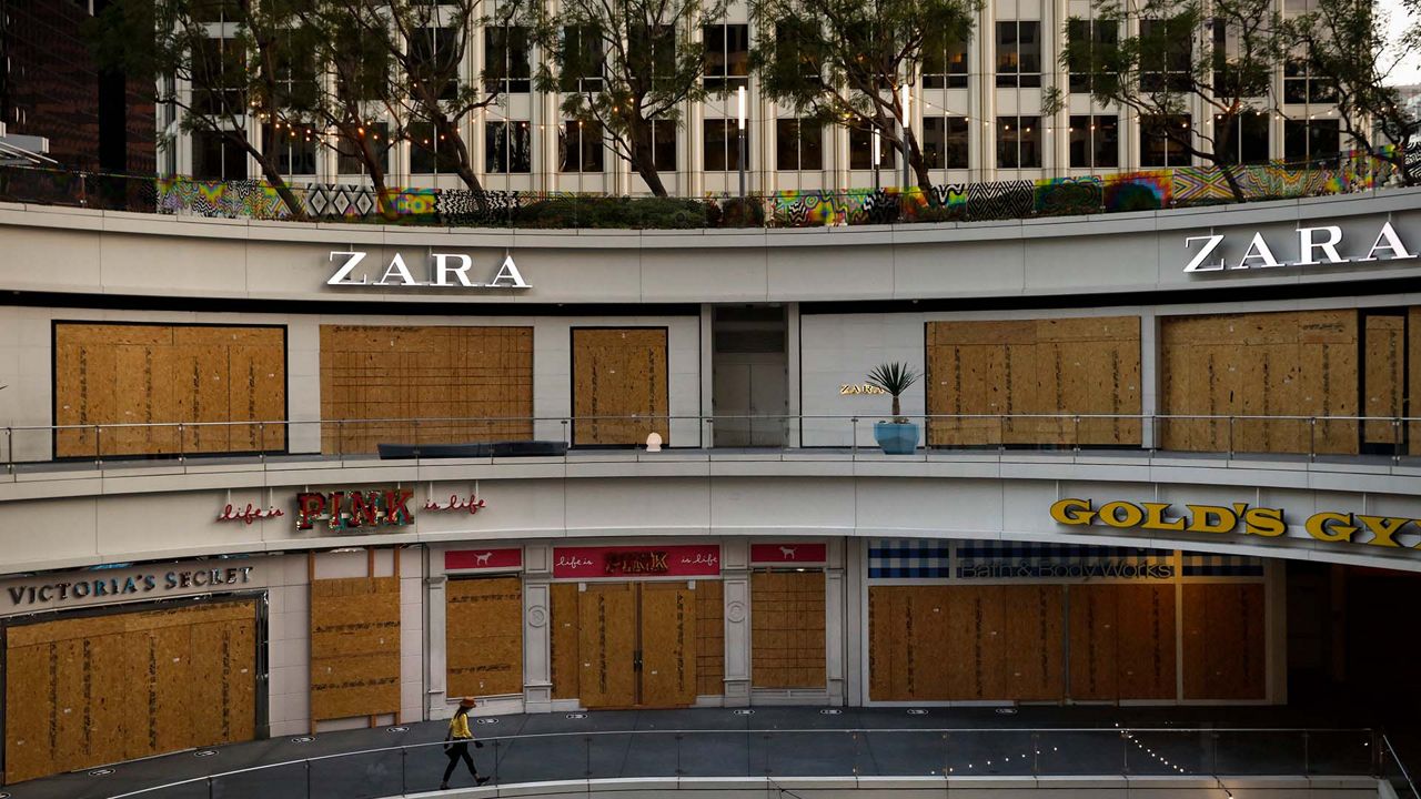 A woman walks past shops covered in plywood panels to protect the properties against potential vandalism and looting on June 3, 2020, in downtown Los Angeles, as protests continued over the death of George Floyd on May 25 in Minneapolis. Los Angeles County pushed back the start of its curfew from 6 p.m. to 9 p.m., a help to newly reopened restaurants and retail stores that were shut down for weeks by anti-coronavirus orders. (AP Photo/Jae C. Hong)