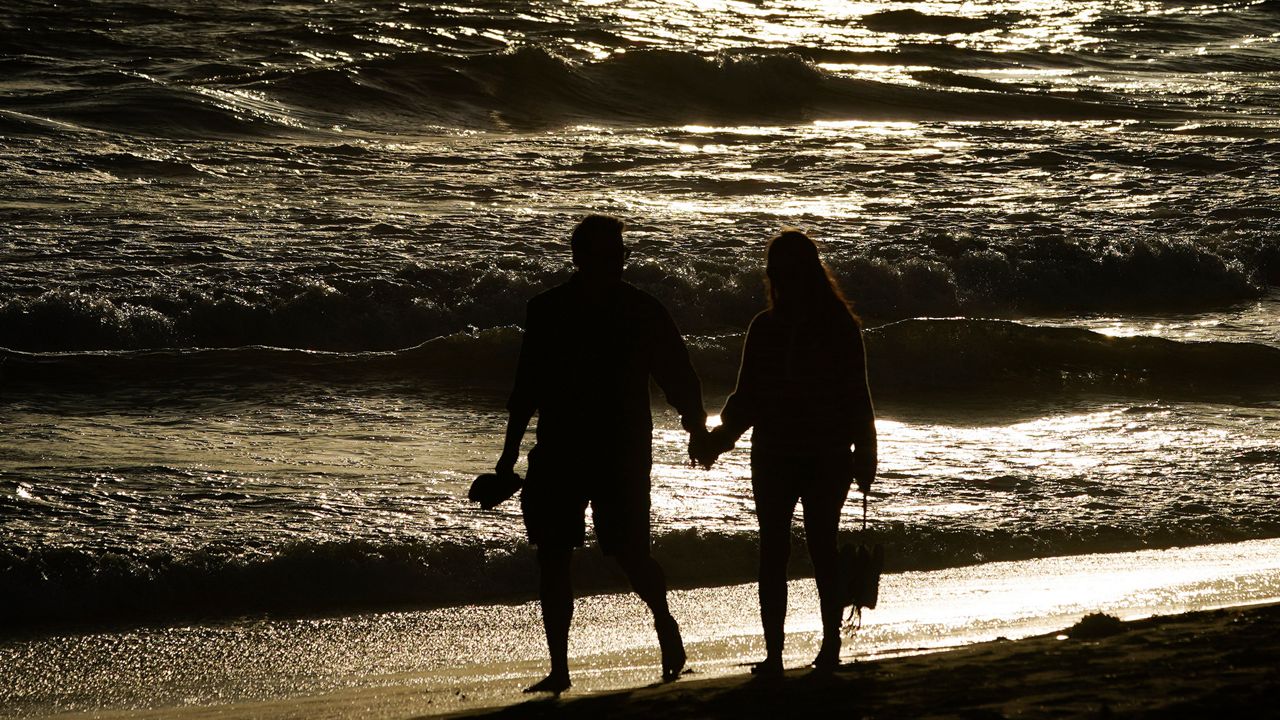 A couple walks on the sand on May 5, 2020, in Huntington Beach. California Gov. Gavin Newsom's administration approved plans by Huntington Beach and two smaller cities to reopen beaches that fell under his order shutting down the entire Orange County coast after a heat wave drew large crowds to the shore. (AP Photo/Chris Carlson)
