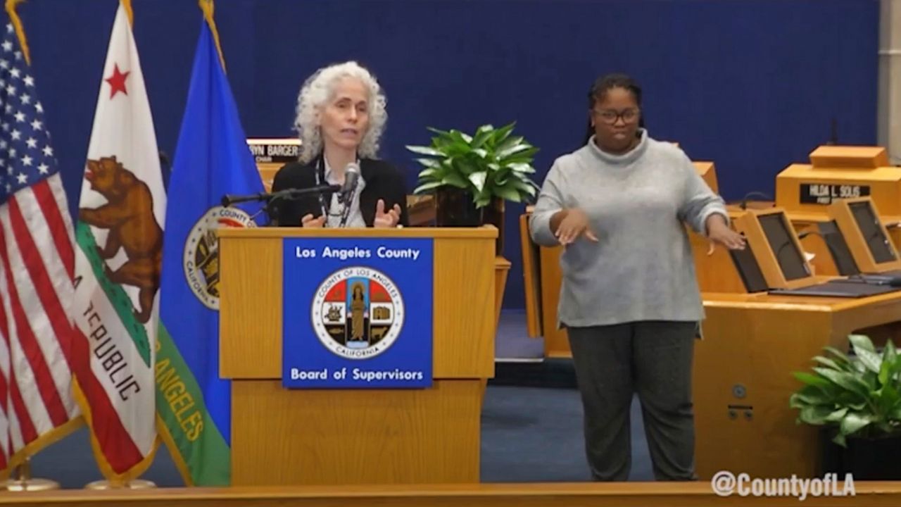 In this April 9, 2020, image made from video provided by the County of Los Angeles, Barbara Ferrer, director of the Los Angeles County Department of Public Health, in Los Angeles gives her daily update on the coronavirus outbreak in the county. At right is Rorri Burton, a sign language interpreter. (County of Los Angeles via AP)