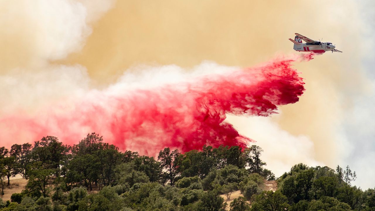 In this file photo from June 9, 2019, a Cal Fire aircraft drops fire retardant on a hillside in an attempt to box in flames from a wildfire called the Sand Fire in Rumsey, Calif. (AP Photo/Josh Edelson)