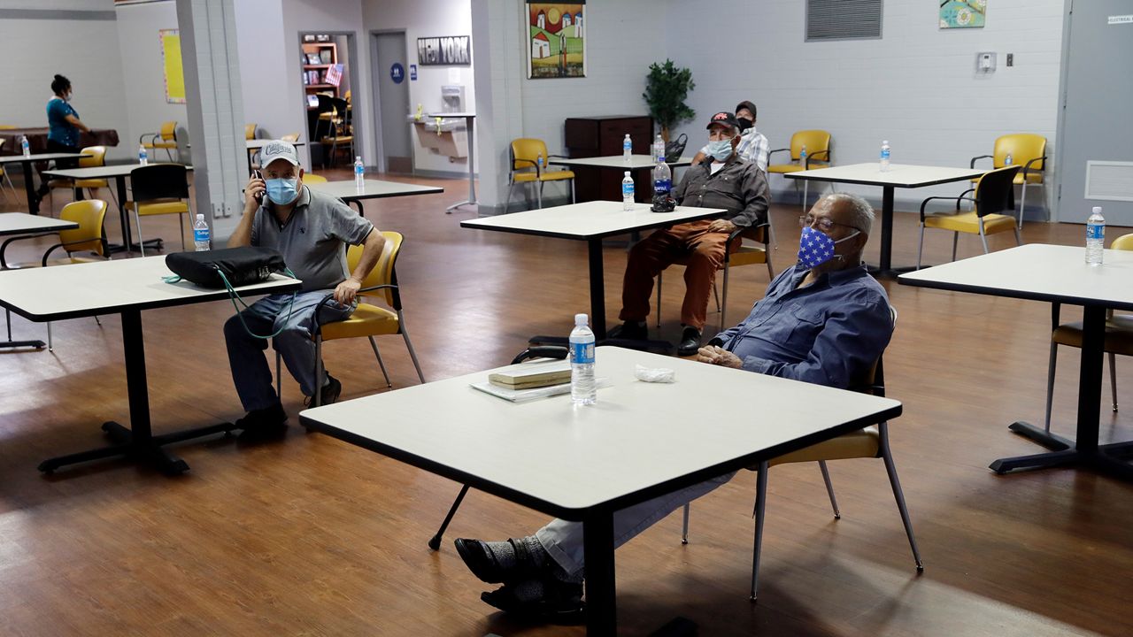 In this file photo from May 6, 2020, men sit following social-distancing rules inside an air-conditioned room at a cooling center as temperatures rise amid the COVID-19 pandemic in Los Angeles. (AP Photo/Marcio Jose Sanchez)