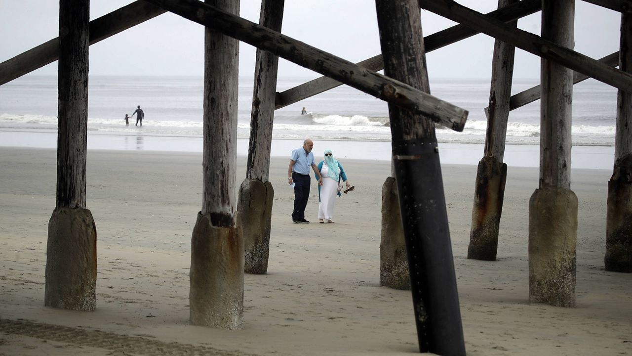 In this file photo from April 30, 2020, a couple walks on the beach in Newport Beach. (AP Photo/Marcio Jose Sanchez)