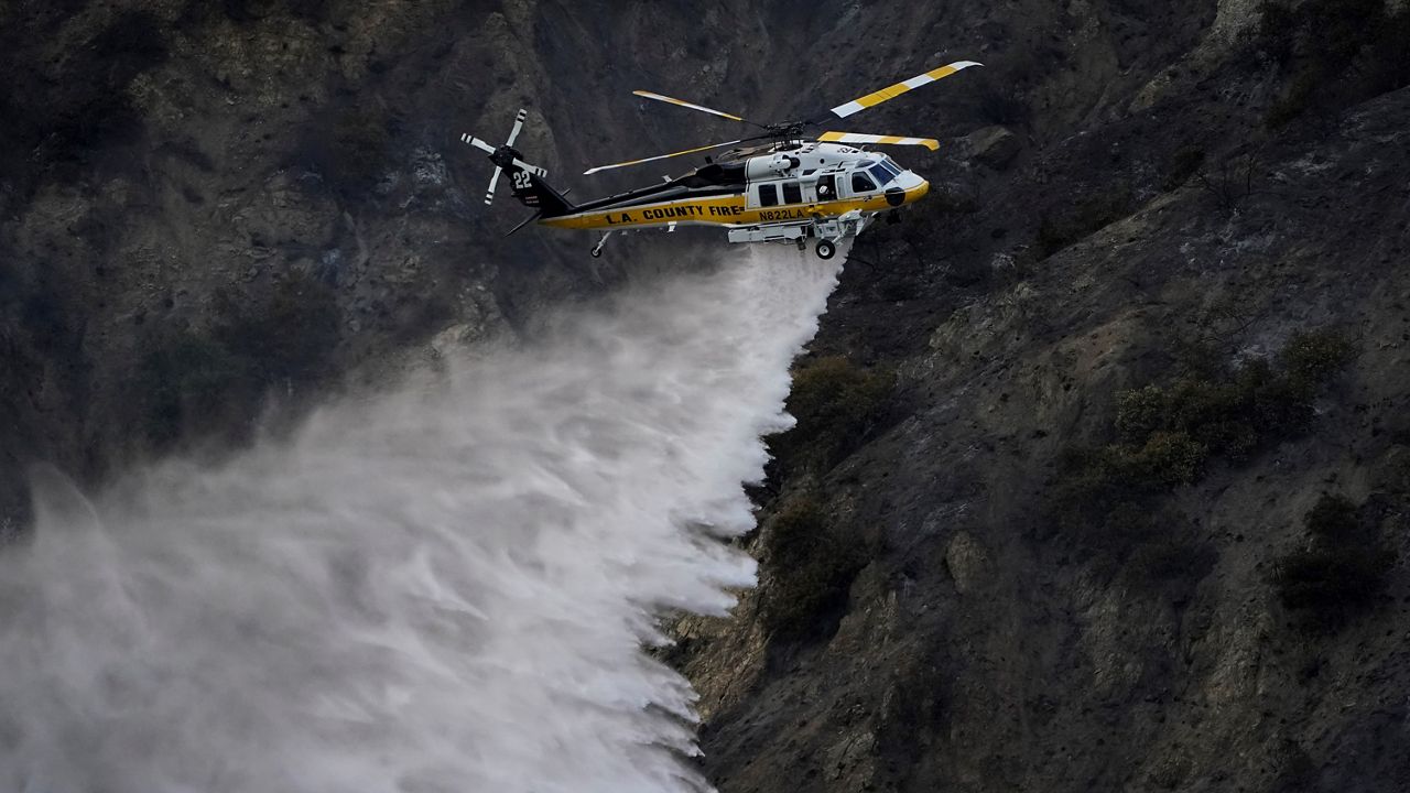 A helicopter makes a water drop over the Ranch Fire on Aug. 13, 2020, in Azusa. (AP Photo/Marcio Jose Sanchez)