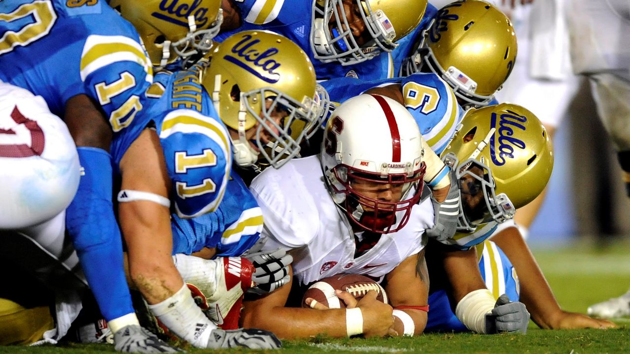 In this file photo from Sept. 11, 2010, UCLA's defender gang tackle Stanford running back Tyler Gaffney during the second half of an NCAA college football game in Pasadena. UCLA has sued Under Armour alleging the company used the pandemic as a "pretext" to dissolve its $280 million agreement. (AP Photo/Gus Ruelas, File)