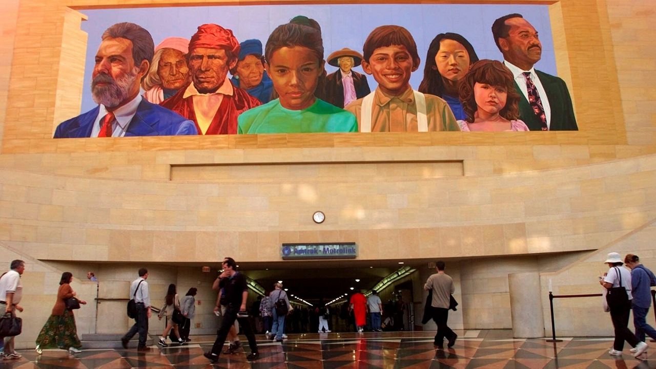 In this file photo from Aug. 30, 2000, commuters walk into a tunnel at L.A.'s Union Station under the mural "City of Dreams/River of History" by artist Richard Wyatt. California moved closer Saturday to requiring corporate boards to include racial or sexual minorities. (AP Photo/Damian Dovarganes)