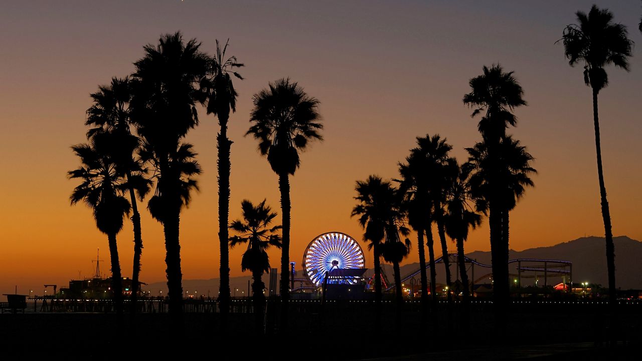 FILE - In this Oct. 11, 2013 file photo, the Ferris wheel at Pacific Park on the Santa Monica Pier is illuminated in Santa Monica, Calif. Santa Monica, a sun-splashed beach city of 92,000 people not only has a famous funky old pier and miles of beautiful beaches but enough museums, art galleries, historic landmarks, chic shopping districts, hipster bars and exquisite restaurants to rival even that giant metropolis to its east. (AP Photo/Mark J. Terrill, File)