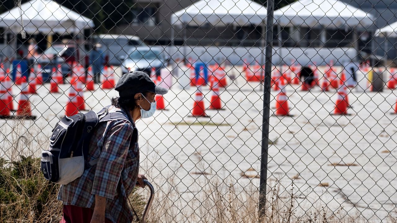 A masked pedestrian walks past a coronavirus testing site in the Panorama City section of Los Angeles on Tuesday, Aug. 3, 2020. 