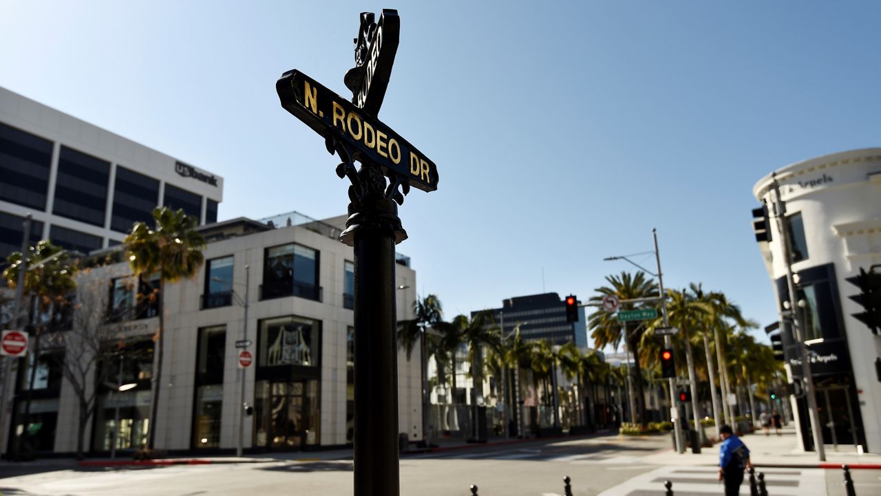 A man waits to cross the street on deserted Rodeo Drive as stay-at-home orders continue in California due to the coronavirus, Monday, March 30, 2020, in Beverly Hills, Calif. (AP Photo/Chris Pizzello)
