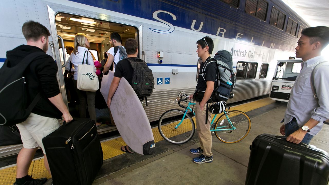 In this file photo from  Nov. 26, 2014, passengers board an Amtrak Surfliner train bound to Santa Barbara at Union Station in Los Angeles, a day before Thanksgiving. (AP Photo/Damian Dovarganes)