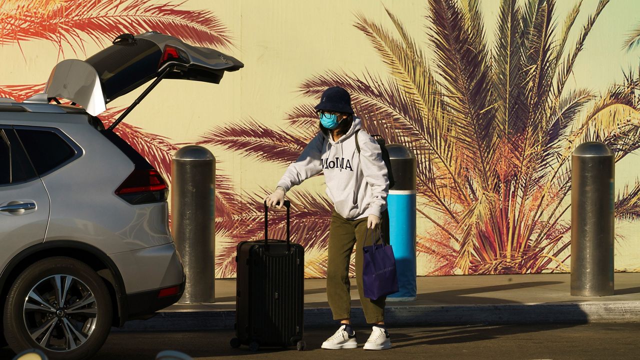 A traveler wears a face mask and gloves at Los Angeles International Airport in Los Angeles Friday, Nov. 13, 2020. California has become the second state to record 1 million confirmed coronavirus infections. (AP Photo/Damian Dovarganes)