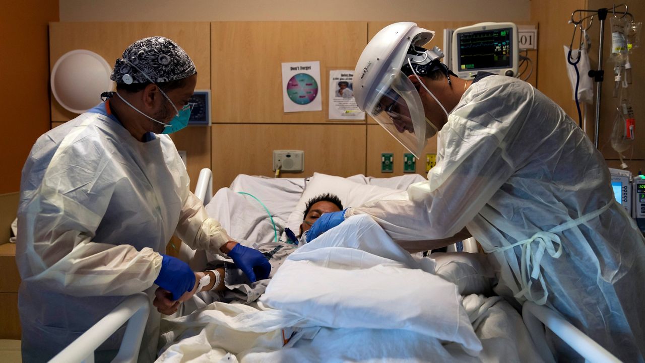 In this Nov. 19, 2020, file photo, Dr. Rafik Abdou, right, and respiratory therapist Babu Paramban check on a COVID-19 patient at Providence Holy Cross Medical Center in the Mission Hills section of Los Angeles. (AP/Jae C. Hong)