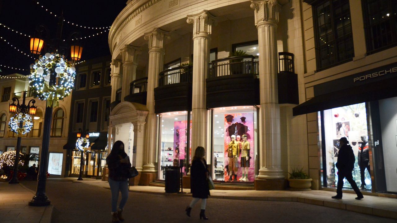 In this Nov. 30, 2020, file photo, people walk on Rodeo Drive, decorated for the holidays amid the coronavirus pandemic in Beverly Hills. (AP Photo/Pamela Hassell)