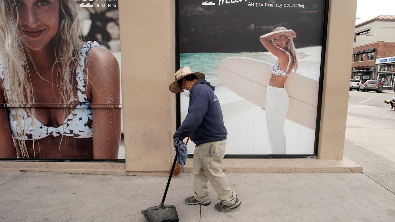 Isabel James cleans Main St. after nonessential businesses and activities are curtailed due to the coronavirus on March 20, 2020, in Huntington Beach, Calif. (AP/Chris Carlson)