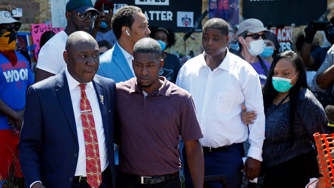 Family attorney Ben Crump, left, escorts Quincy Mason, second from left, a son of George Floyd, Wednesday, June 3, 2020, in Minneapolis, as they and some Floyd family members visited a memorial where Floyd was arrested on May 25 and died while in police custody. Video shared online by a bystander showed a white officer kneeling on his neck during his arrest as he pleaded that he couldn't breathe. (AP Photo/Jim Mone)