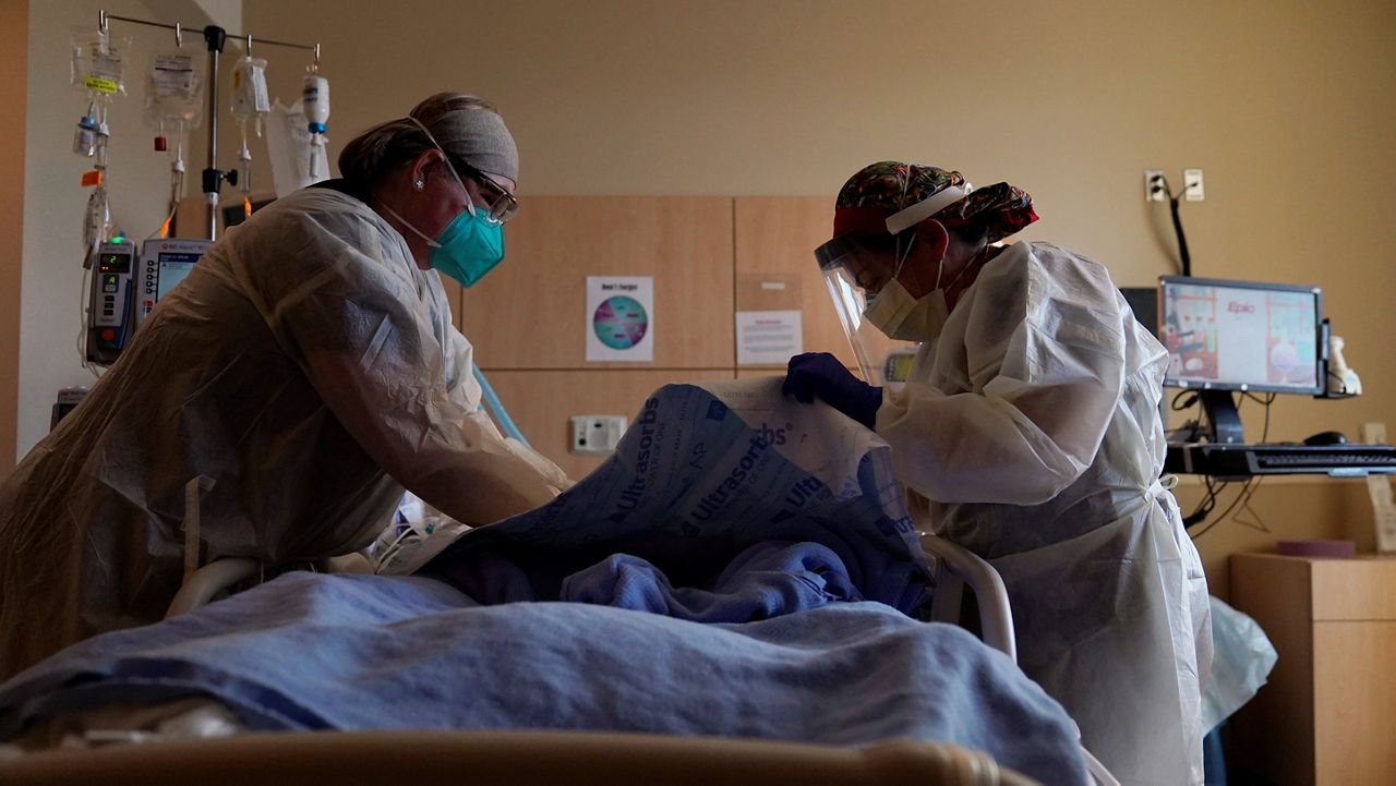 Registered nurses Robin Gooding, left, and Johanna Ortiz treat a COVID-19 patient at Providence Holy Cross Medical Center in Mission Hills on Dec. 22, 2020. (AP Photo/Jae C. Hong)