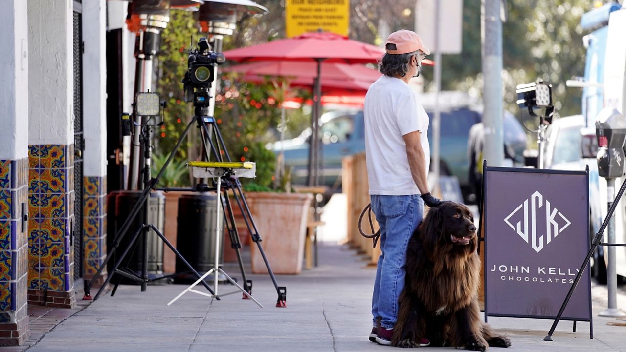 George Ruiz pets his Newfoundland dog Amy near an area on North Sierra Bonita Avenue, where Lady Gaga's dog walker was shot and two of her French bulldogs stolen, Feb. 25, 2021, in Los Angeles. (AP Photo/Chris Pizzello)
