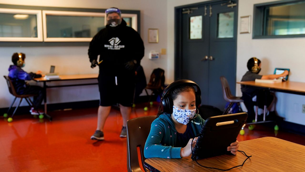 In this Aug. 26, 2020, file photo, Los Angeles Unified School District students attend online classes at Boys & Girls Club of Hollywood in Los Angeles. After weeks of tense negotiations, California legislators agreed Thursday on a $6.5 billion proposal aimed at getting students back in classrooms this spring following months of closures because of the coronavirus pandemic. (AP Photo/Jae C. Hong, File)