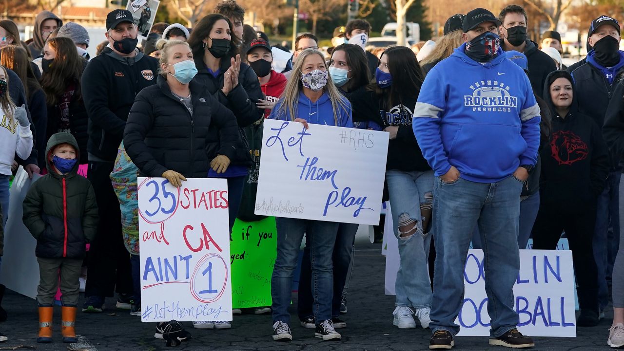 In this January 29, 2021, file photo, people gather at a "Let Them Play Rally" in Citrus Heights, calling for California Gov. Gavin Newsom to allow the state's school children to participate in sports. California public health officials loosened the rules for youth sports on Friday, allowing all outdoor sports to resume in counties where COVID-19 case rates are at or below 14 people per 100,000. (AP Photo/Rich Pedroncelli, File)
