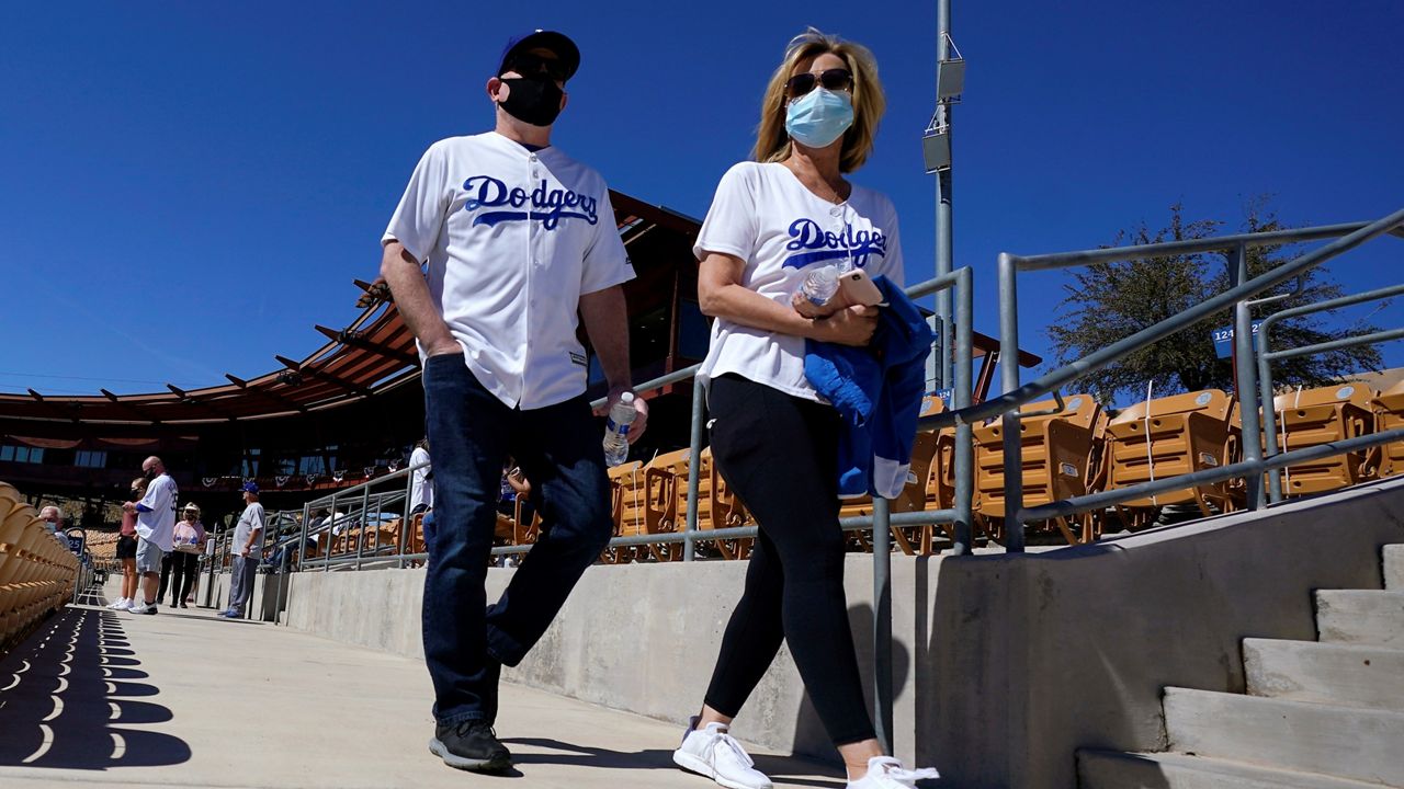 With face coverings on, Los Angeles Dodgers fans walk to their seats before a spring training baseball game against the Colorado Rockies at Camelback Ranch stadium Monday in Phoenix. (AP Photo/Ross D. Franklin)