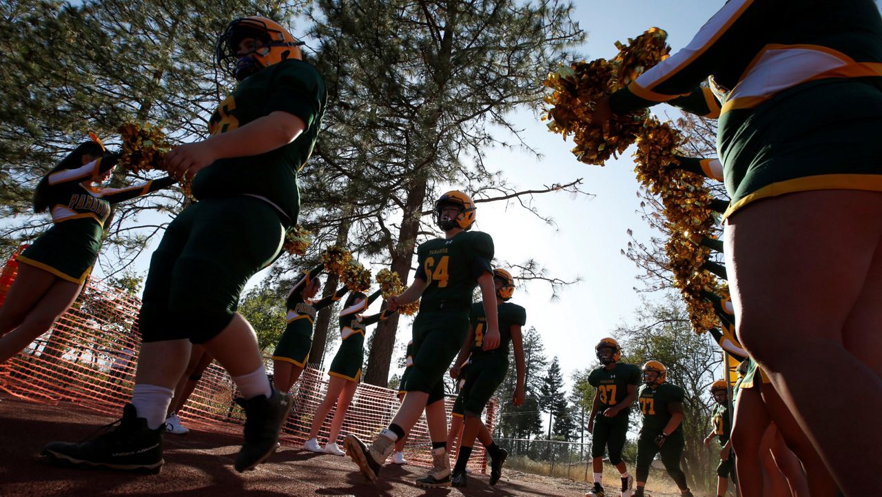 In this August 23, 2019, file photo, the Paradise junior varsity football team walks past cheerleaders and on to the field for their high school football game in Paradise, Calif.  (AP Photo/Rich Pedroncelli, File)