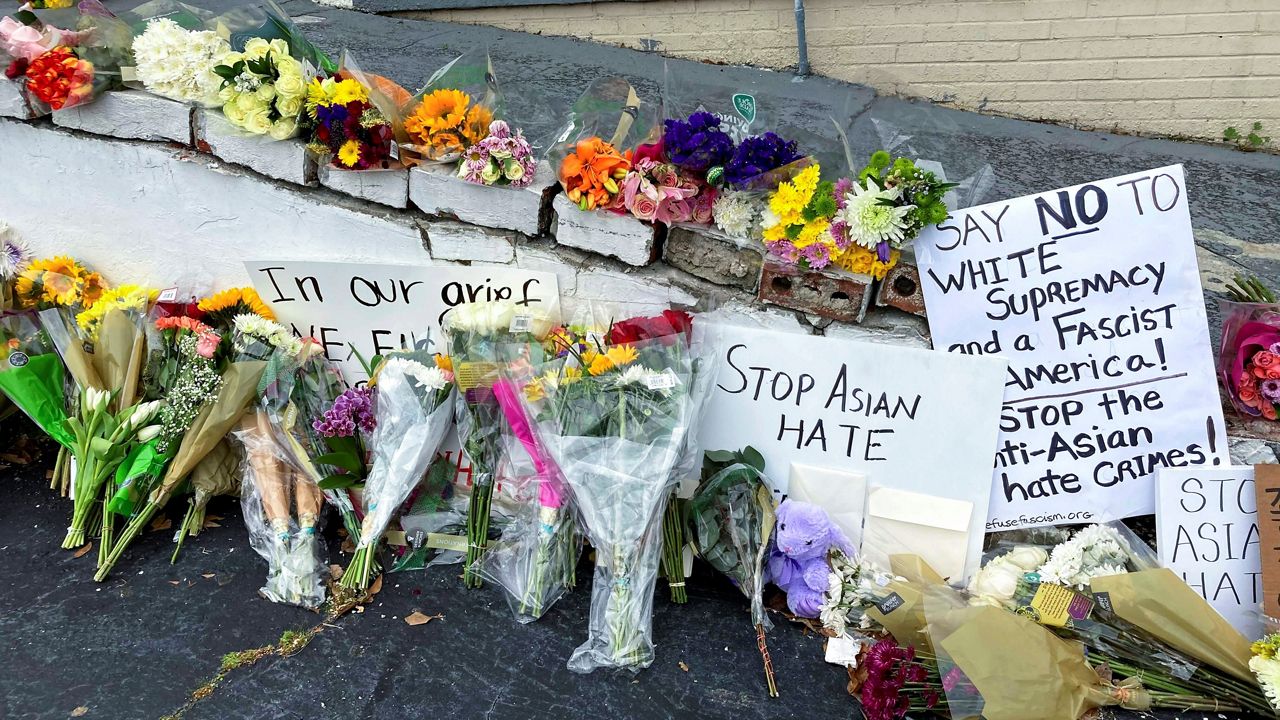 In this March 19, 2021 file photo, flowers, candles, and signs are displayed at a makeshift memorial in Atlanta. (AP Photo/Candice Choi)