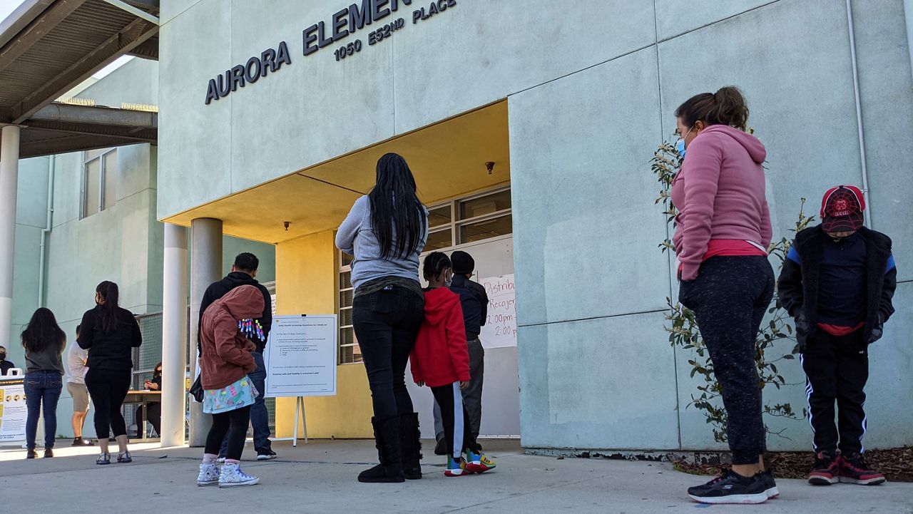 Parents and students line up Tuesday to pick up school materials outside the Aurora Elementary School in Los Angeles. (AP Photo/Damian Dovarganes)