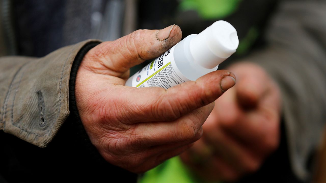 A man holds a bottle of sanitizer. The U.S. Environmental Protection Agency ordered two Glendale companies to stop selling an unregistered disinfectant on Thursday. (AP Photo/John Munson)