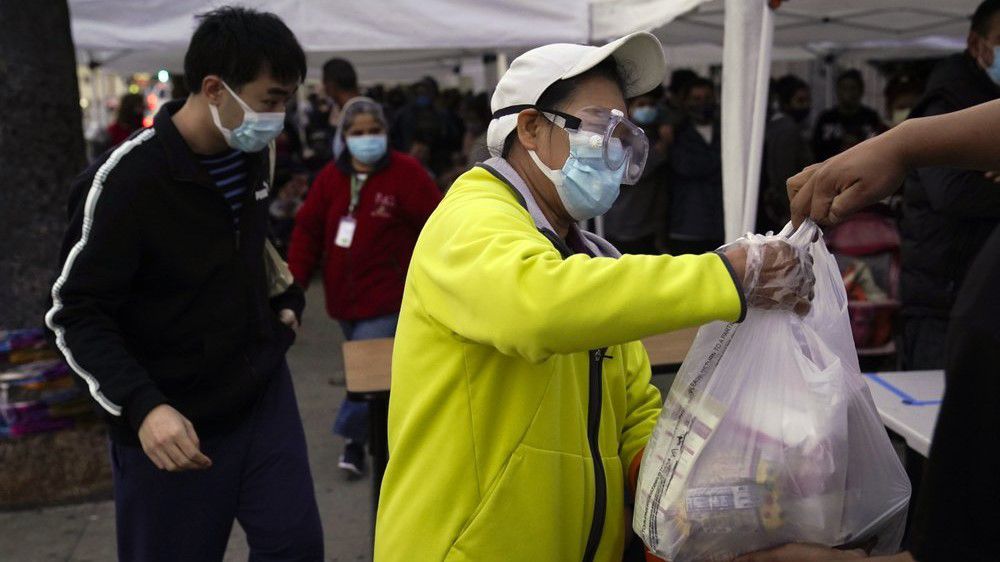 In this Dec. 17, 2020 file photo, a woman receives a bag of groceries at a food bank at the Los Angeles Boys & Girls Club in the Lincoln Heights neighborhood of L.A. (AP Photo/Jae C. Hong)