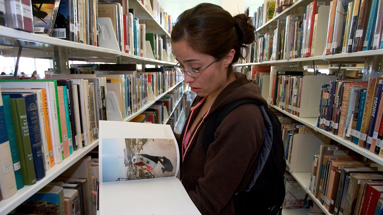 In this March 18, 2008, file photo, Wendy Barranco, a college student and Iraq war veteran, looks at a photographic book on Iraq at the Pasadena City College library in Pasadena. 