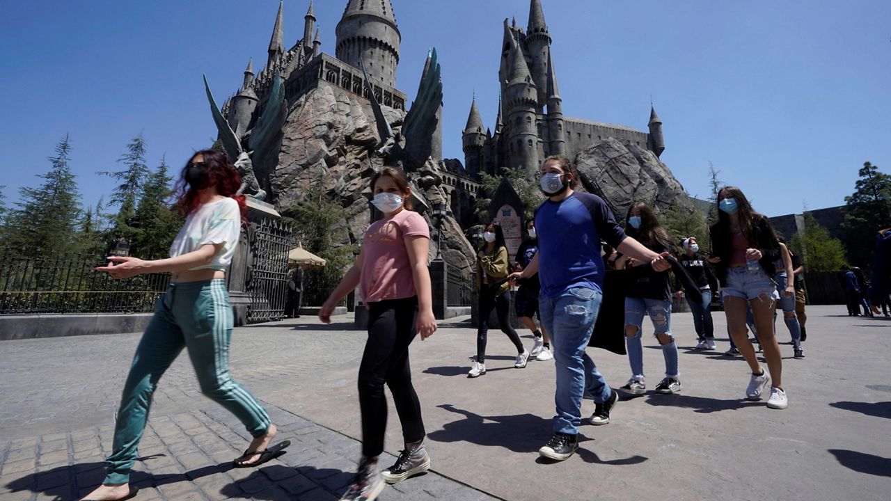 Young people wear mandatory face masks at the Wizarding World of Harry Potter at Universal Studios Hollywood theme park as it officially reopens to the public at 25% capacity with COVID-19 protocols in place in Los Angeles, Friday. (AP Photo/Damian Dovarganes)