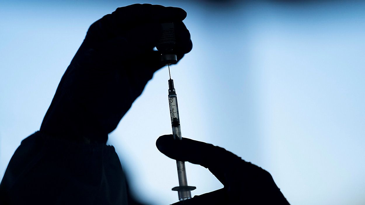 Someone draws a COVID vaccine into a vial. (Associated Press)