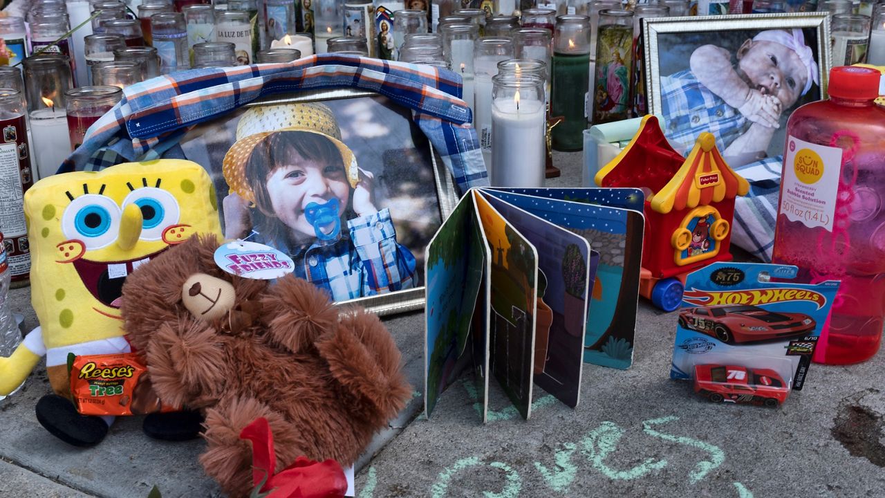 In this April 12, 2021, file photo, photos, candles, flowers and balloons are placed as a memorial for three children who were killed at the Royal Villa apartments complex in Reseda. (AP Photo/Richard Vogel, File)