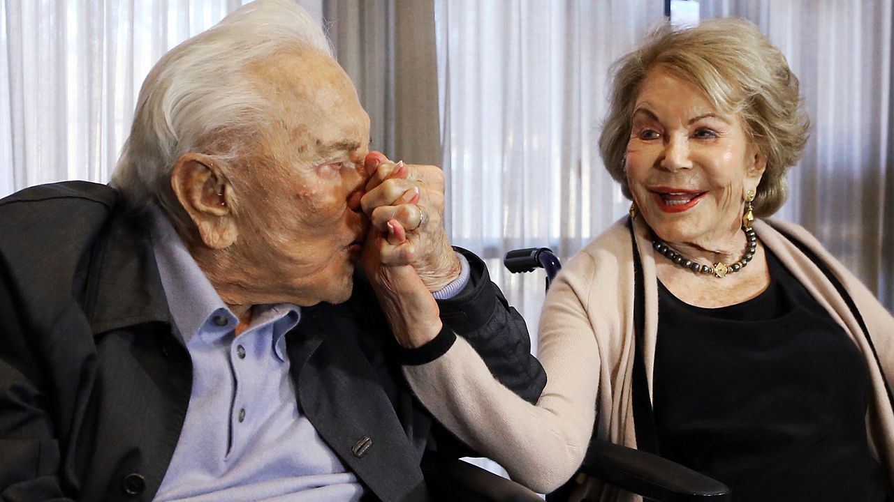 In this May 4, 2017, file photo, Kirk Douglas kisses his wife Anne's hand in Los Angeles during a party celebrating his 100th birthday. Anne Douglas, the widow of Kirk Douglas and stepmother of Michael Douglas, died Thursday in California. (AP Photo/Reed Saxon, File)
