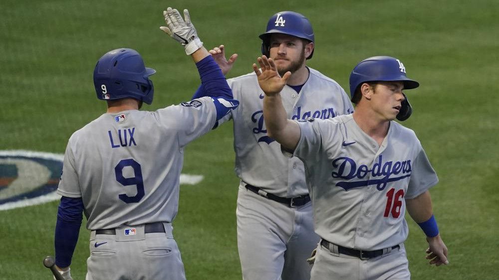 Los Angeles Dodgers' Gavin Lux (9) high-fives Max Muncy (13) and Will Smith (16) after they scored off of a line drive hit by Matt Beaty during the fourth inning of a baseball game Saturday against the Los Angeles Angels in Anaheim. (AP Photo/Ashley Landis)