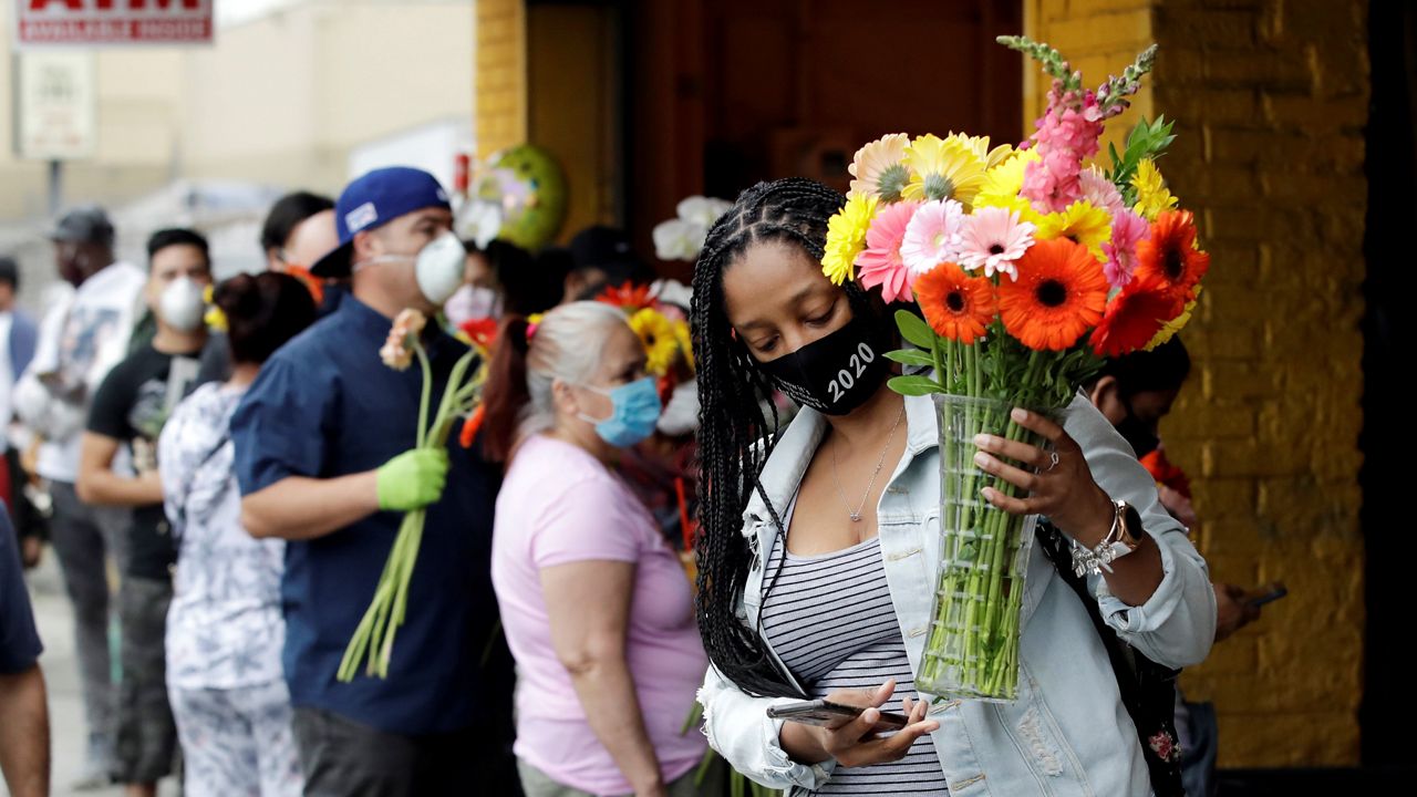 Customers line up to by flowers on Mother's Day at the Los Angeles Flower Market, Sunday, May 10, 2020, in Los Angeles. Families in the U.S. and elsewhere marked Mother's Day in a time of social distancing and isolation due to the coronavirus pandemic. (AP Photo/Marcio Jose Sanchez)