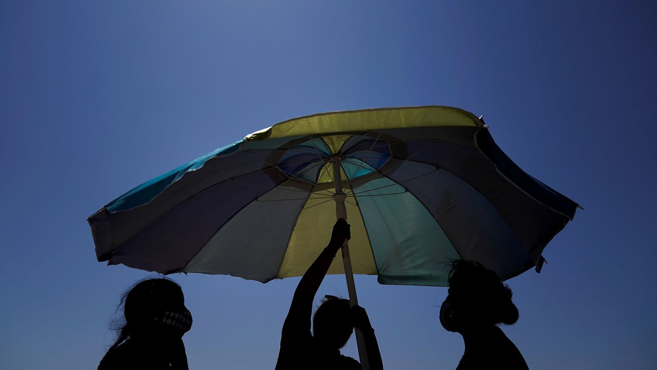 Beachgoers set up an umbrella on the beach on Sept. 5, 2020, in Huntington Beach, Calif. (AP Photo/Jae C. Hong)