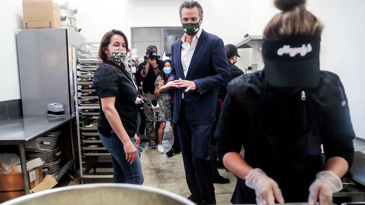 In this April 29, 2021, file photo, Elva Quinonez prepares food as California Gov. Gavin Newsom talks with Magaly Colelli at Magaly's restaurant in San Fernando. (Robert Gauthier/Los Angeles Times via AP, Pool, File)